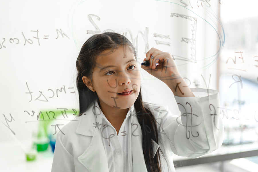 Cute little girl student child learning research and doing a chemical experiment and write scientific formulas and calculations in physics at science class.Education and science concept