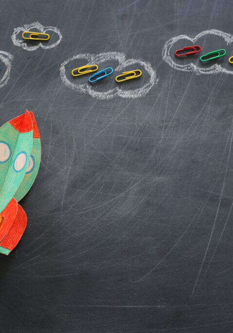 education. Back to school concept. rocket cut from paper and painted over blackboard background. top view, flat lay